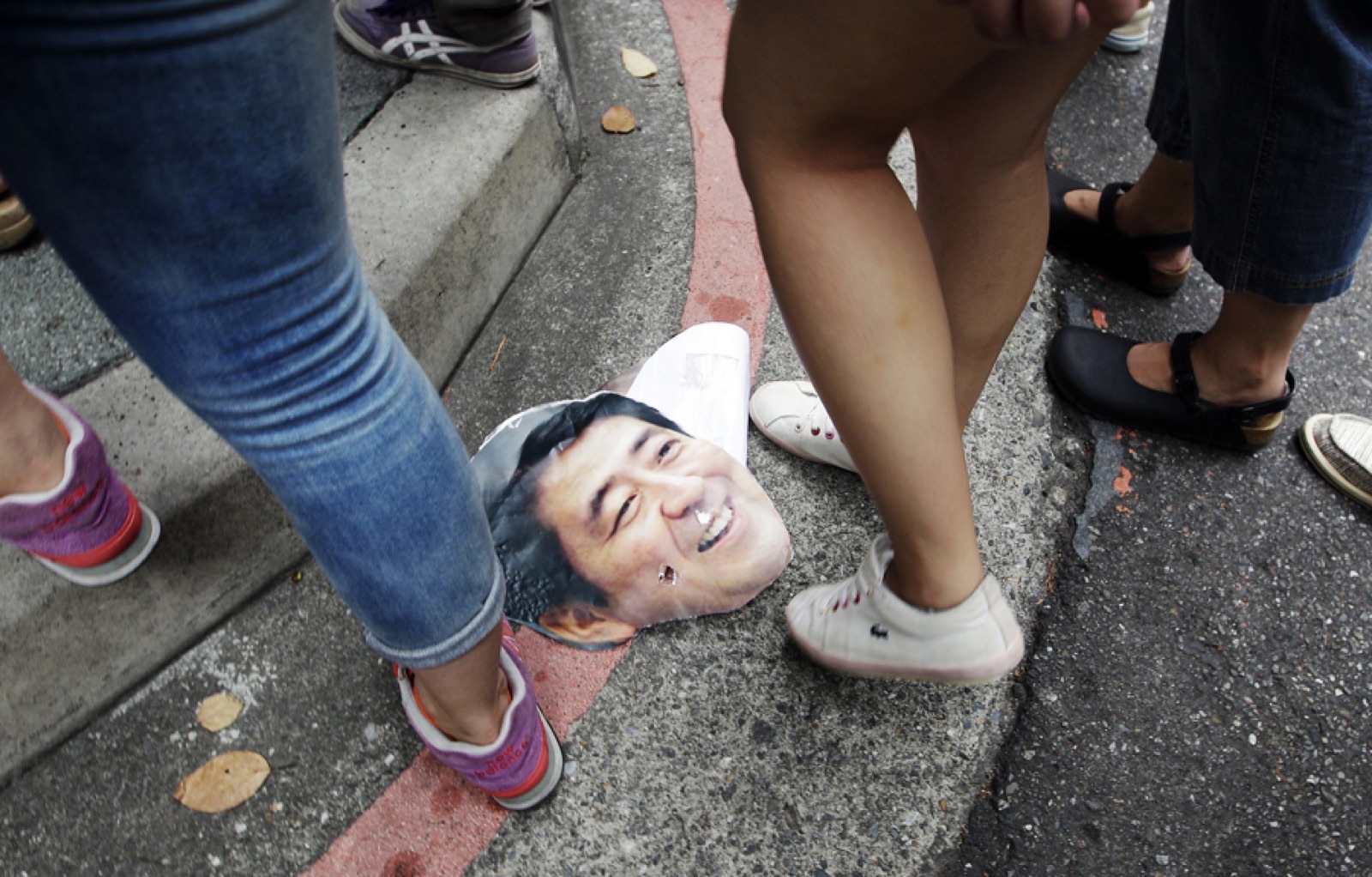Activists step over a picture of Shinzo Abe during a protest in front of the Japan Interchange Association in Taipei